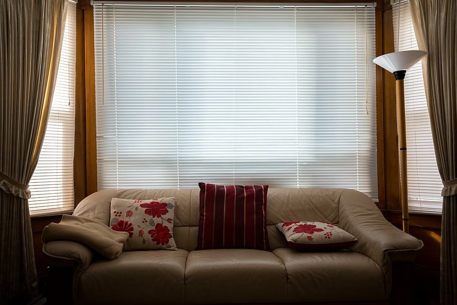 White blinds in a living room behind a sofa