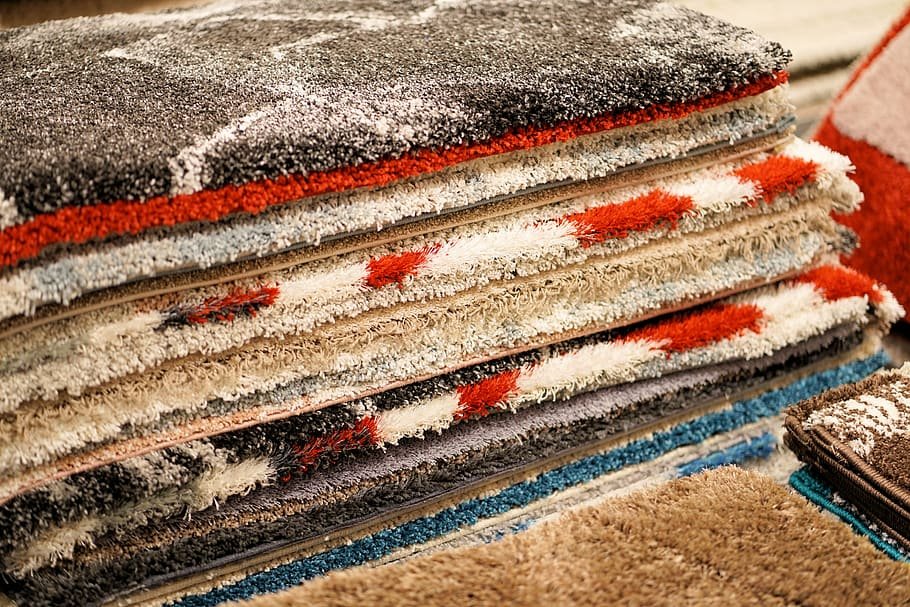 A pile of colorful patterned rugs stacked on top of each other